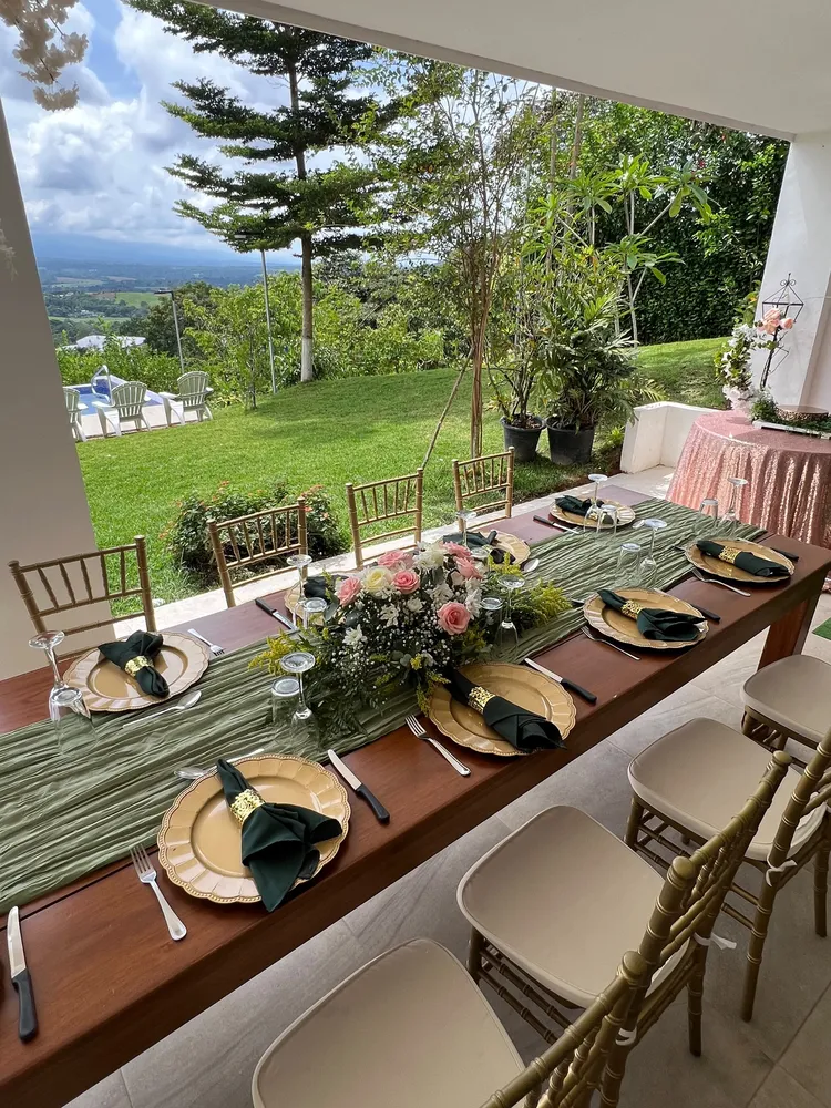 Mesa larga decorada en verde y dorado con vista a las montañas