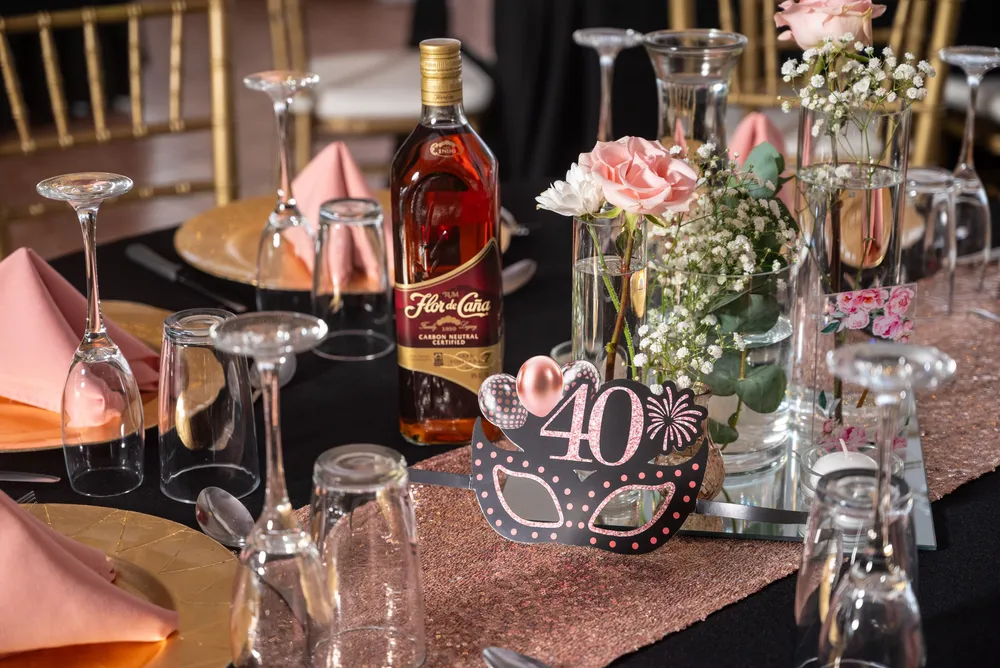 Mesa de cumpleaños número 40 en negro y rosado con copas doradas