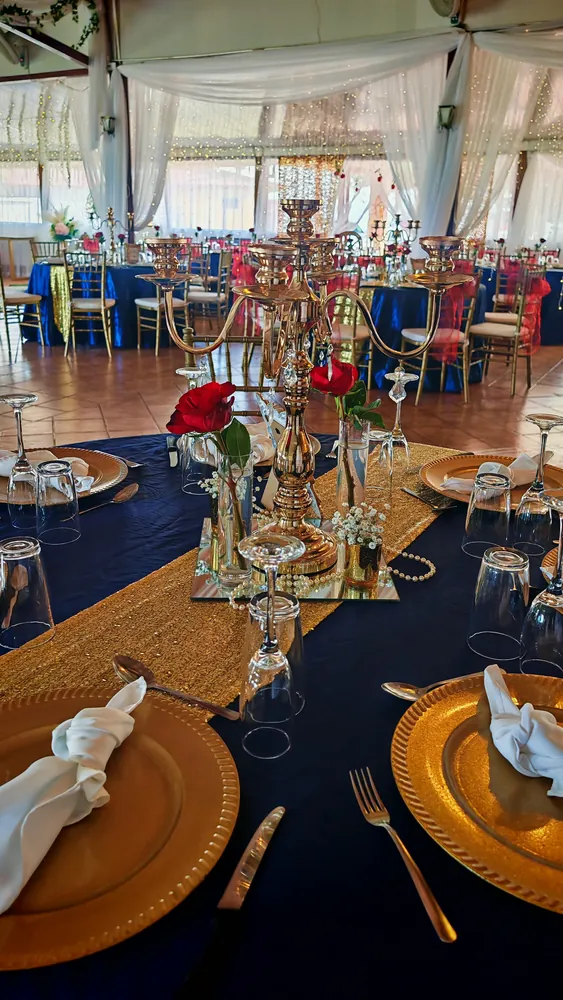 Candelabro dorado con rosas rojas sobre mantel azul marino